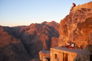 Hikers resting on a rocky summit in the Sinai mountains at sunrise